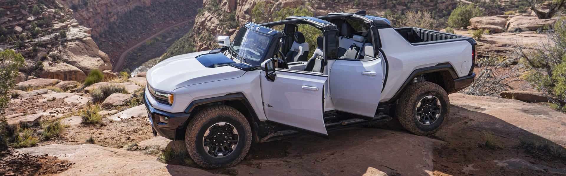 2025 GMC Hummer EV pickup truck in Interstellar White at Folsom Buick GMC in FOLSOM, CA photographed on rugged desert terrain with open doors