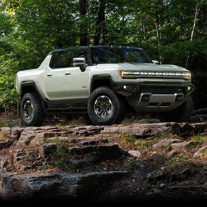 GMC Hummer EV from Folsom Buick GMC FOLSOM CA positioned on rocky cliff edge surrounded by forest