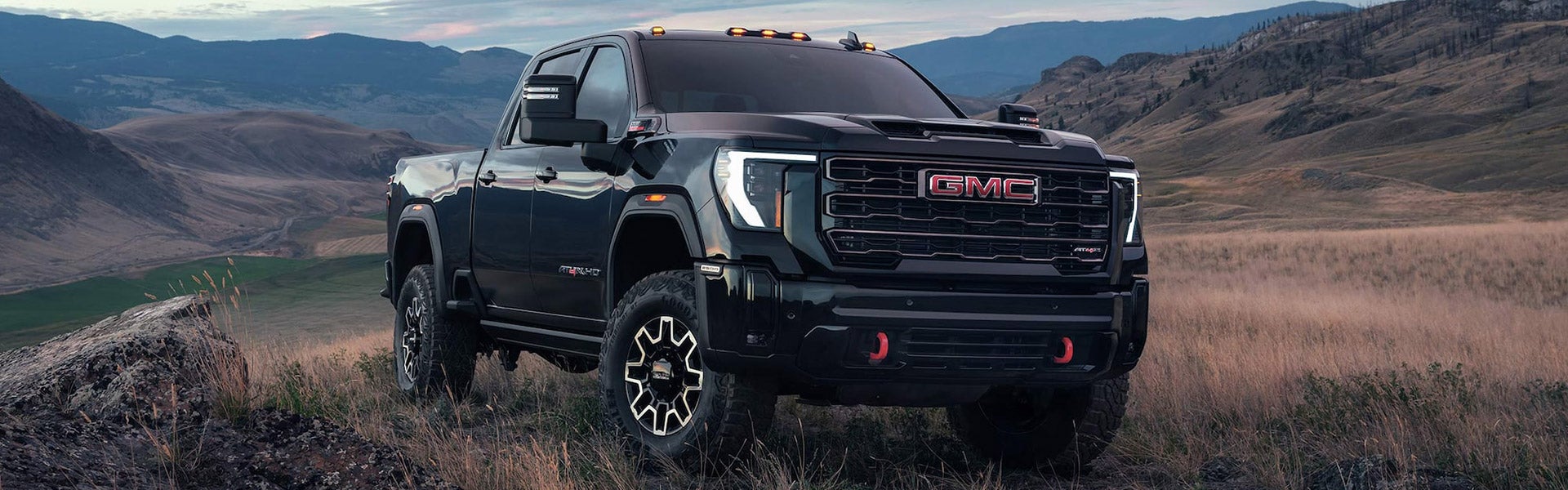 2025 GMC Sierra 2500HD AT4X from Folsom Buick GMC in FOLSOM, CA in Onyx Black displaying off-road capabilities against mountain backdrop with LED signature lighting